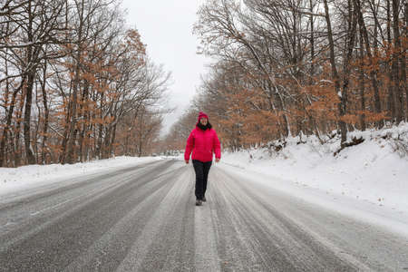 A woman walks down the snow-white road, all around the forest of snow-white oak trees. Winter landscape.の写真素材