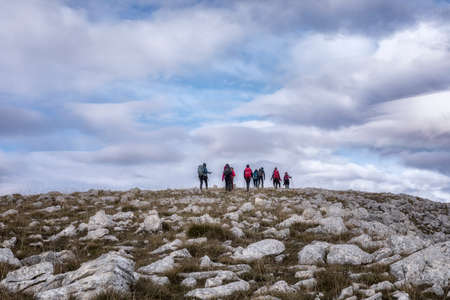 Mountaintop hikers explore the area during the fall season. Autumn landscape on the top of the mountain, rocky surface and beech forest in the distance.の写真素材