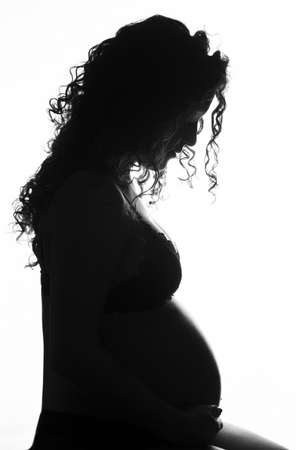 Profile of pregnant woman with a swollen belly. Pregnancy of young woman, profile in backlight.の写真素材