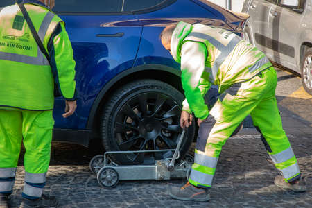 Naples, Italy - March 25, 2022: Removal with the tow truck of a parked car in no parking. Fine and...