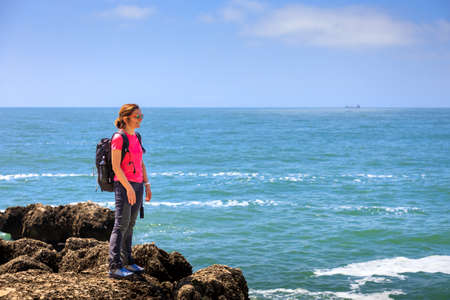 Woman hiker explores the rocky sea coast. Concept of healthy life and outdoor activities in contact with nature.の写真素材