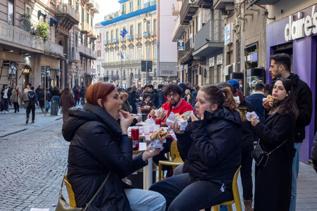 Naples, Italy - February 13, 2023: citizens and tourists eat in the street, in the city centre, sitting at the tables of a fast-food restaurant.のeditorial素材