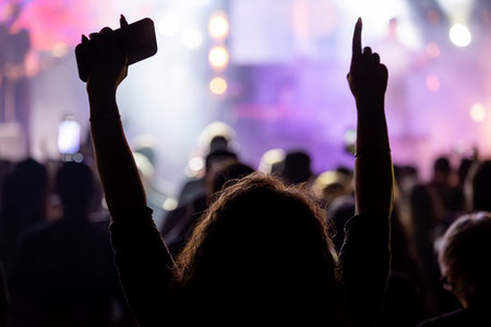 The audience gets excited and cheers with their arms raised during the concert of the musical band...