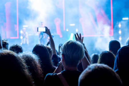 The audience records videos and takes photos with their smartphones during the concert of the...