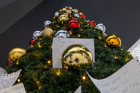 Naples, Italy - December 11, 2024: The Christmas tree set up at the train station, and people...