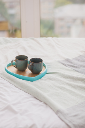 Two blue mugs on a tray white bed, breakfast conceptの写真素材