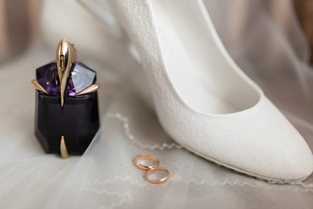 Wedding accessories bride. White shoes, perfume, wedding rings on a light backgroundの写真素材