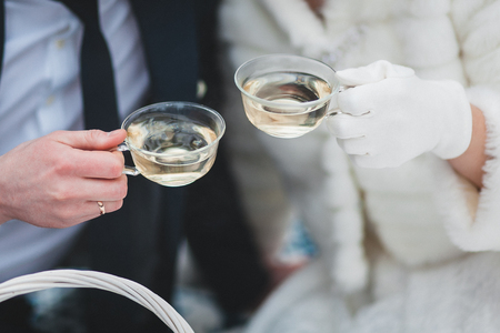 The bride and groom are holding a cup of tea in their hands. Close-upの写真素材