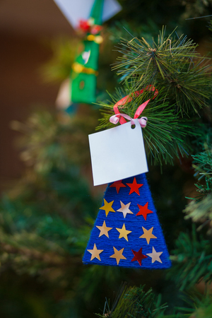 Handmade knitted toy and empty postcard hanging on a Christmas treeの写真素材