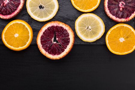 Fresh ripe citruses. Lemons, limes and oranges on dark stone background. Top view with copy spaceの写真素材