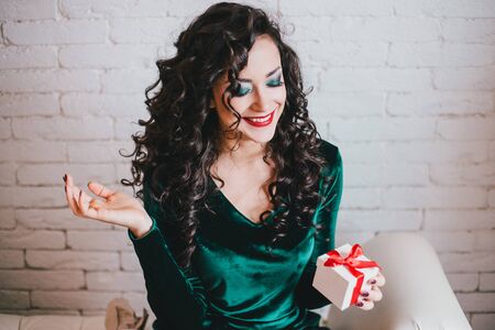 Woman with red lipstick in green velvet dress and red shoes and gift. Valentine's Dayの写真素材
