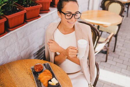 Young beautiful business woman wearing glasses having french breakfast in Paris street cafeの写真素材