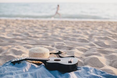 Still life with straw hat and ukulele on the beach. Summer concept.の写真素材