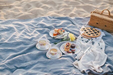 Beautiful picnic with pancakes, jam, american pie and tea on sunset at beach.の写真素材