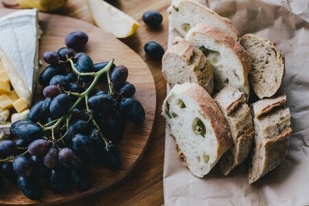 Table with wine, cheese, bread, grapes and pears standing on a cozy balcony in a wooden country...