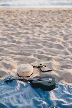 Still life with straw hat and ukulele on the beach. Summer concept.の写真素材