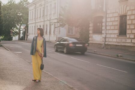Young beautiful fashion woman wearing stylish yellow jumpsuit posing on european city streets.の写真素材