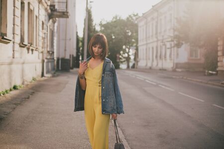 Young beautiful fashion woman wearing stylish yellow jumpsuit posing on european city streets.の写真素材