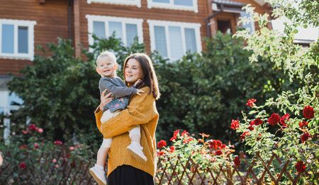 Young happy mother and her baby posing near their new cozy wooden house.の写真素材