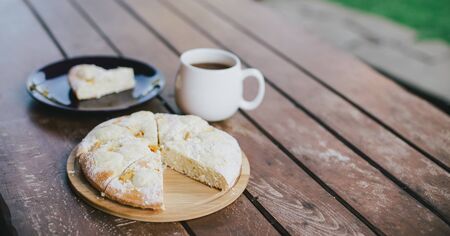 Fresh homemade peach pie and hot black tea on a cozy terrase.の写真素材