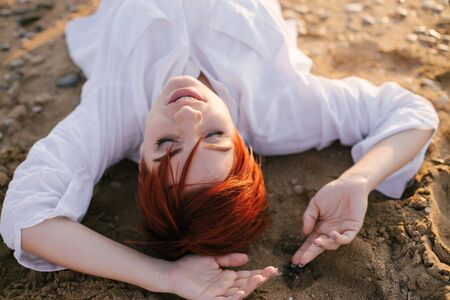 Beautiful sensual woman with short haircut posing on the beach at sunset.の写真素材