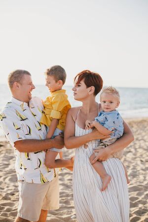 Happy family having fun with their little children on beach at sunset