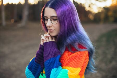 Girl teenager with bright violet blue hair wearing colorful knitted sweater in a forest.の写真素材