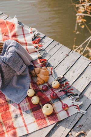 Picnic on the lake: fresh croissants and apples. Breakfast on fresh air near autumn forest.の写真素材