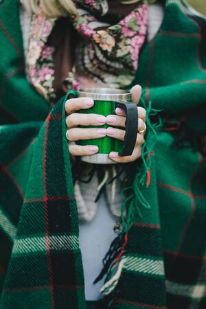 Green cup with hot tea close up in an autumn forestの写真素材