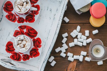 Two cups of hot cocoa with marshmallows and cinnamon on wooden background. Valentine's Day