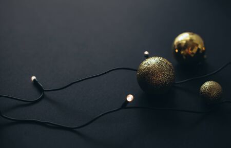 Black and golden Christmas decorations and festive lights on black background.の写真素材