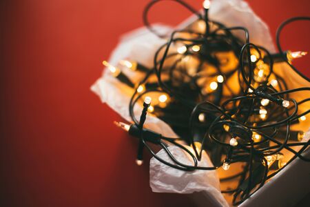 Box with golden Christmas garland on red background. Place for text.の写真素材