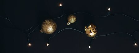 Black and golden Christmas decorations and festive lights on black background.の写真素材