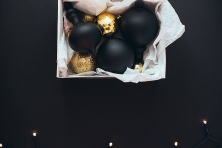 Close up box with vintage Christmas black and golden decorations and festive lights on black background.の写真素材