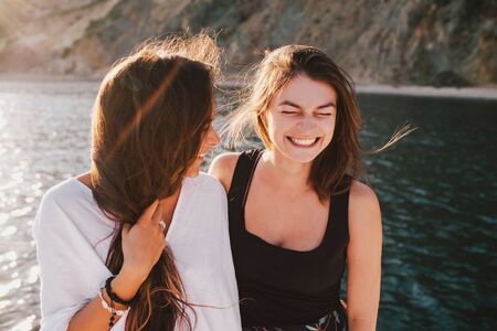 Two young women friends posing on yacht with beautiful ocean view on the background.の写真素材