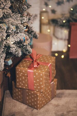 Presents under the vintage Christmas tree with festive lights on backgroundの写真素材