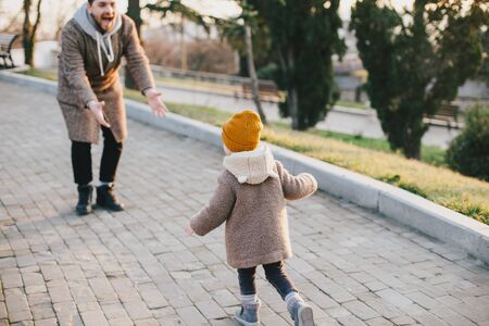Stylish father hipster with beard and tattoo walking with his little daughter. Fashion family look.