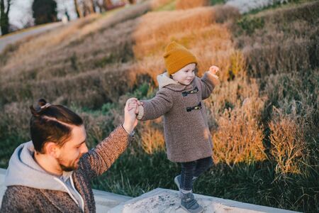 Stylish father hipster with beard and tattoo walking with his little daughter. Fashion family look.の写真素材