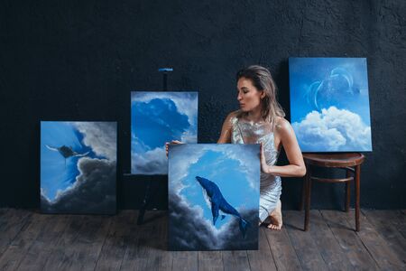 Beautiful woman artist with creative fantasy make up posing with her paintings.の写真素材