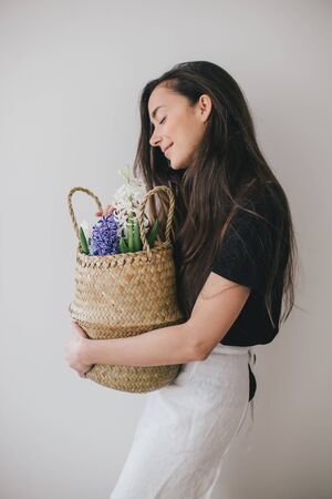Young beautiful woman with long hair holding basket with hyacinth flowers on white background. Place for text.の写真素材