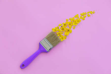 Creative layout with paint brush and yellow wild flowers on pink background. Brush paints with flowers. Copy spaceの写真素材