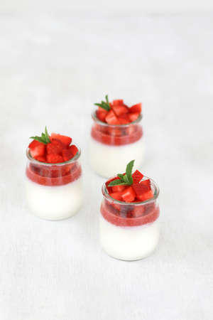 Italian dessert panna cotta with fruit jelly and fresh pieces of strawberries on white background. Copy spaceの写真素材