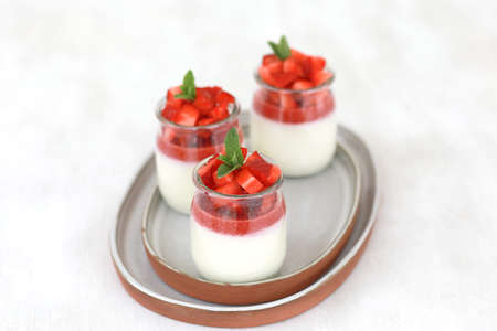 Italian dessert panna cotta with fruit jelly and fresh pieces of strawberries on white background. Copy spaceの写真素材