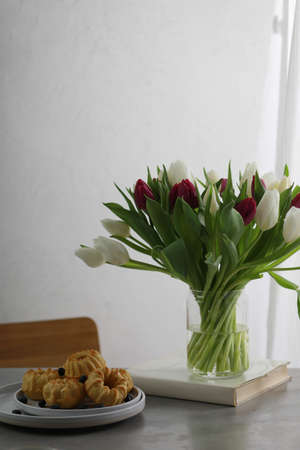 Mini bundt cakes with fruits on plate, cup of coffe and bouquet of tulips.の写真素材