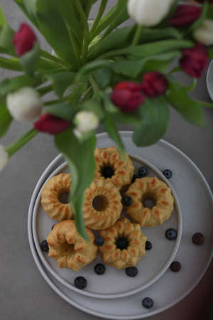 Mini bundt cakes with fruits on plate and bouquet of tulips. Breakfastの写真素材