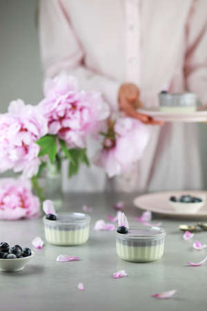 Homemade Italian dessert panna cotta with blue berries and bouquet of peony flowers on gray background.の写真素材