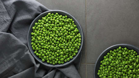 Fresh green peas in plates on a gray background. Top view.の写真素材