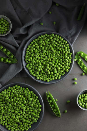 Fresh green peas in plates on a gray background. Top view.の写真素材