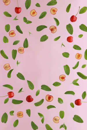 Summer background, frame with fresh cherry fruits and mint on pink background. Flat lay. Summer fruits concept.の写真素材