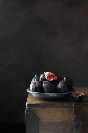 Black fresh figs in a metalic plate on dark background. Copy spaceの写真素材